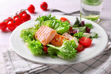 Plate with tasty grilled fish and fresh salad on table