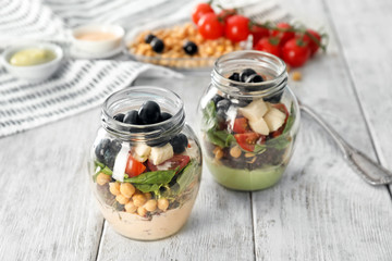 Delicious vegetable salad in jars on wooden table