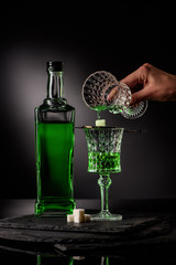 cropped shot of woman pouring absinthe in glass and on sugar cube on dark background