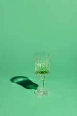 crystal glass of absinthe beverage on green surface