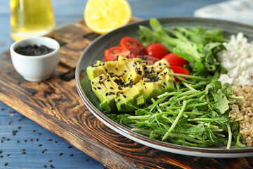 Plate with delicious healthy fresh salad on wooden board