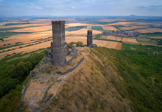 Aerial view on two stone towers  ruins of mediaeval castle Hazmburk, Hasenburg built on top of the mountain peak, surrounded by agriculture czech landscape. Aerial photography in Czech republic.