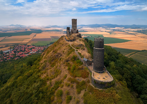 Aerial view on two stone towers  ruins of mediaeval castle Hazmburk, Hasenburg built on top of the mountain peak, surrounded by agriculture czech landscape. Aerial photography in Czech republic.