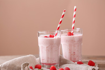 Glasses with tasty raspberry smoothie on table against color background