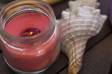 an aromatic burning candle and a sea shell in a beauty studio and massages. accessories and relaxation requisites for a beauty and health parlor.