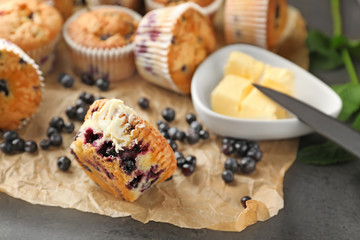 Tasty blueberry muffins with butter on table