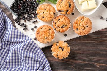 Board with tasty blueberry muffins on wooden table