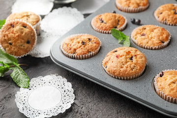 Baking tin with tasty blueberry muffins on table