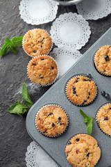 Baking tin with tasty blueberry muffins on table