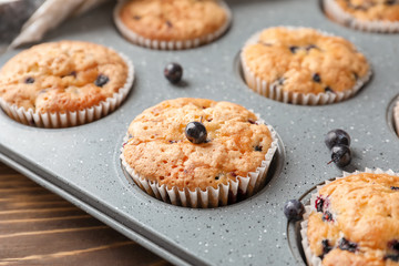 Tasty blueberry muffins in baking tin, closeup