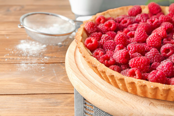 Tasty pie with fresh raspberries on wooden table