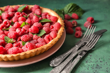 Tasty pie with fresh raspberries on color table