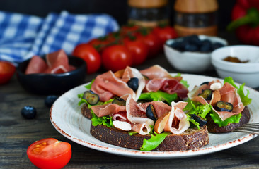 Toast of rye bread with jamon, blueberries and almonds. Snack with a proshoto!