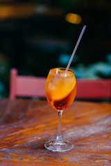 Vertical shot of fresh sweet aperol spiritz cocktail with slice of orange, on wooden table in cafe. Restaurant apertif drink. Summer time concept