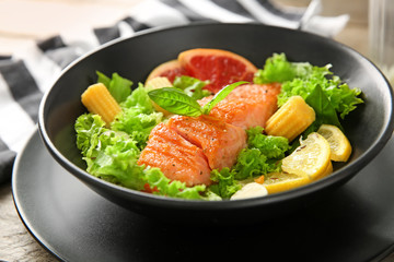 Bowl with fresh salad and fish on table, closeup