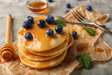 Delicious pancakes with berries and honey on light table