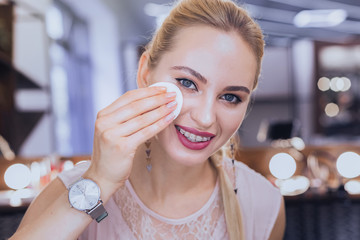 Dental brackets. Blonde-haired appealing stylish woman wearing dental brackets taking makeup off