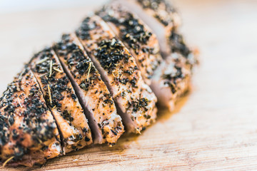 Sliced baked in spices fillet of chicken breast on a wooden cutting board