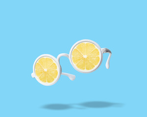 White sunglasses with lemon on bright blue background. Summer minimal concept.