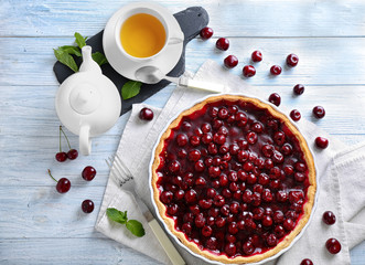 Tasty homemade cherry pie and cup of hot tea on white wooden table
