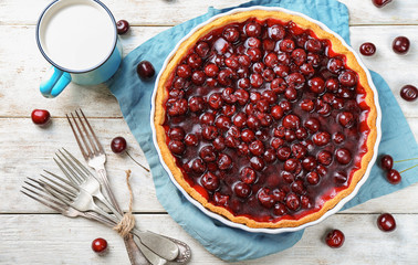 Tasty homemade cherry pie and cup of milk on white wooden table