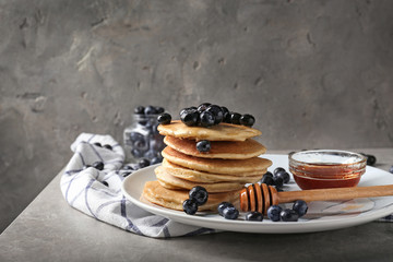Plate with delicious pancakes and berries on light table
