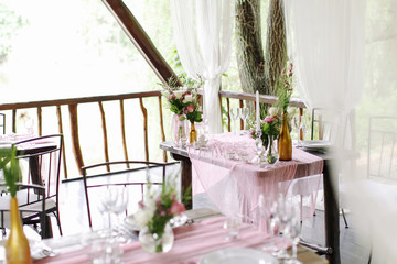 Wedding. Banquet. The festive table for guests, decorated with a composition of white and pink...