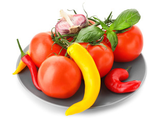 Plate with ripe cherry tomatoes, vegetables and basil on white background