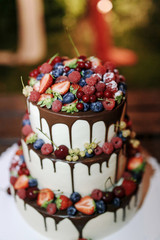 Wedding Strawberry blueberry raspberry berries cake with chocolate on a wooden background in evening outdoor. Close up