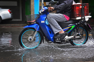 Fototapeta na wymiar Motorcycle drive through the flood on the road, flooding in Bangkok city, flooding on the road, flooding in the city