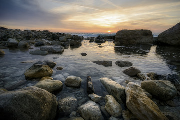 Fototapeta na wymiar seascape at sunrise with rock and calm Water against vibrant sky .