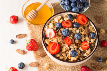 Healthy breakfast concept with oat flakes and fresh berries on rustic background. Food made of granola, muesli. Healthy banana smoothie with blackberries, muslie, strawberries, blueberries and honey.