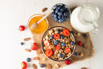 Healthy breakfast concept with oat flakes and fresh berries on rustic background. Food made of granola, muesli. Healthy banana smoothie with blackberries, muslie, strawberries, blueberries and honey.