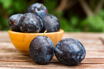 Fresh ripe plums in wooden bowl close