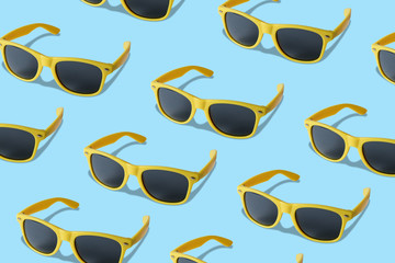 Yellow sunglasses pattern on pastel blue background. Minimal summer concept. Flat lay.