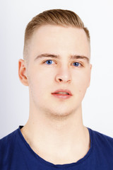 Young man in blue shirt poses in studio, close up portrait