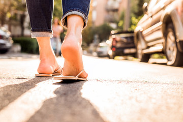 Woman wearing FlipFlops walking down the street on a sunny summer day- closeup of the feet