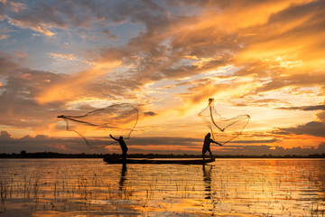 Fototapeta premium Two fisherman cast a net at lake in the moring time , silhouette light