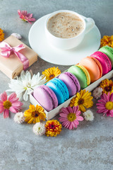 Obraz na płótnie Canvas Photo of cake macarons, gift box, tea, coffee, cappuccino and flowers. Sweet romantic food macaroon concept. Morning breakfast and presents. Valentine's day concept.