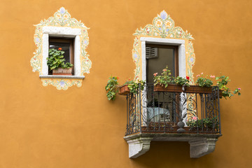 Fototapeta na wymiar Window and balcony with floral decorations on an ancient house