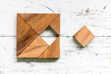 Tangram puzzle in square shape that wait to fulfill on old white wood background