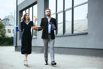 couple in luxury outfit with soda drinks and italian pizza walking on street