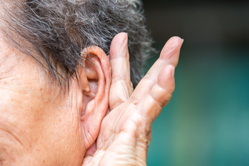 Naklejka premium Senior woman holding hand to left ear, trying to listen, Close up
