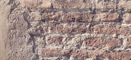 Old grungy red and white brick wall with damaged plaster banner background texture.