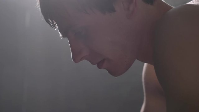 Extreme close shot of sweaty shirtless boxer, drops of water on his face macro