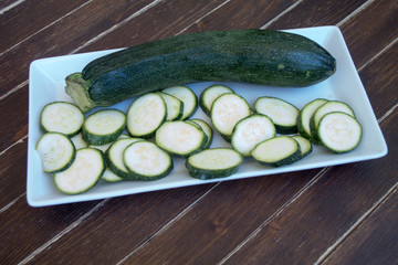 zucchini in a white tray on a wooden table seen close up