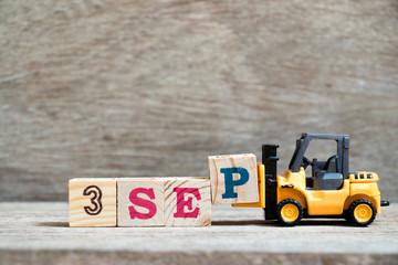 Toy forklift hold block P to complete word 3 sep on wood background (Concept for calendar date in month September)