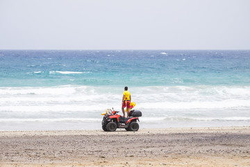 lifeguard on motorbike check and look on the ocean to verify the security of the beach. sand ocean vacation concept