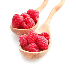 Wooden spoons with sweet ripe raspberries on white background