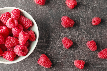 Bowl with sweet ripe raspberries on grey background